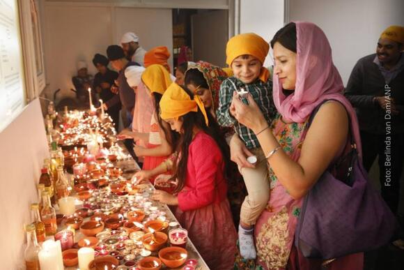 Divali viering in Amsterdam, bezoekers steken kaarsjes aan in een tempel