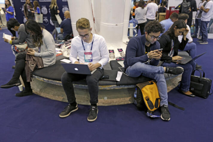 Several participants to the Web Summit 2017 using their smartphones and laptops