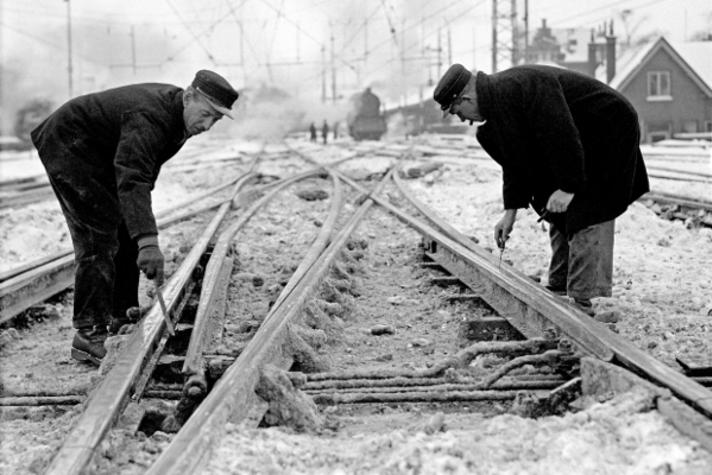 Een spoorwissel wordt onderhanden genomen door medewerkers van de Nederlandse Spoorwegen